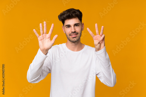 Young man over isolated orange background counting eight with fingers