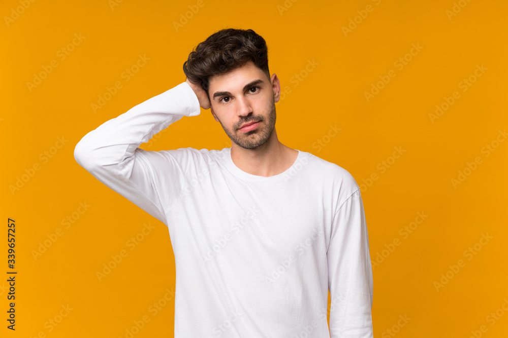 Young man over isolated orange background with an expression of frustration and not understanding Young man over isolated orange background with an expression of frustration and not understanding