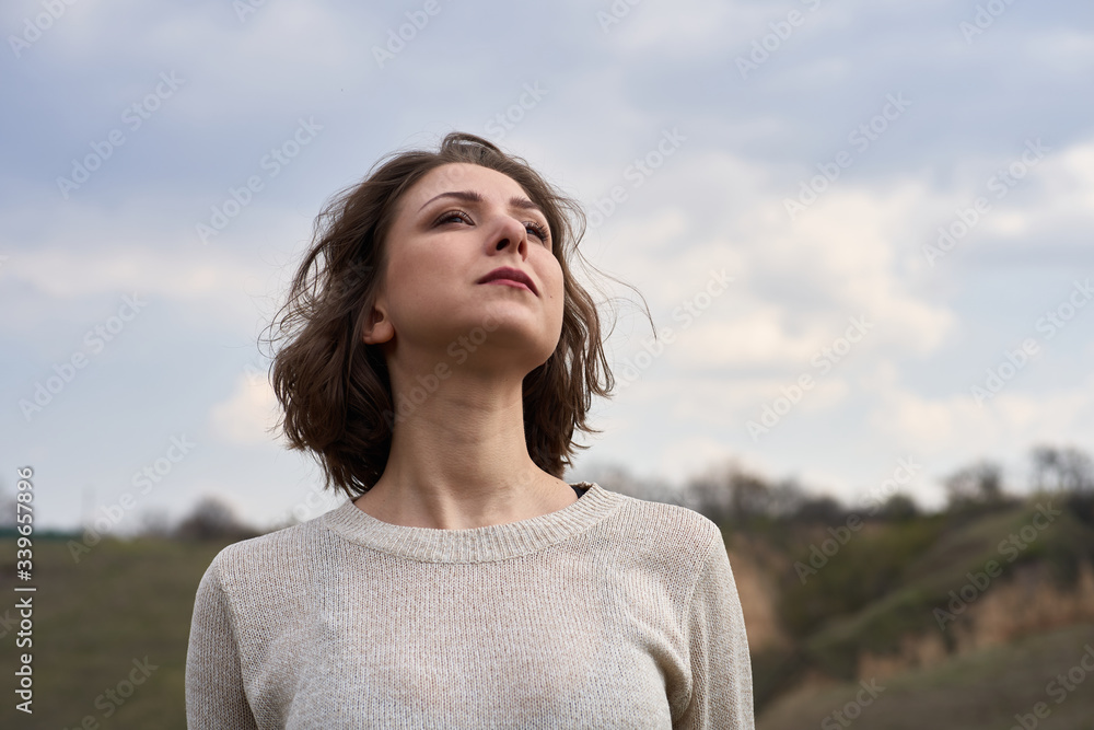 Portrait of beautiful girl on nature view background with hills and sky. Young woman is looking thoughtfully, isolated outdoor Portrait of beautiful girl on nature view background with hills and sky. Young woman is looking thoughtfully, isolated outdoor