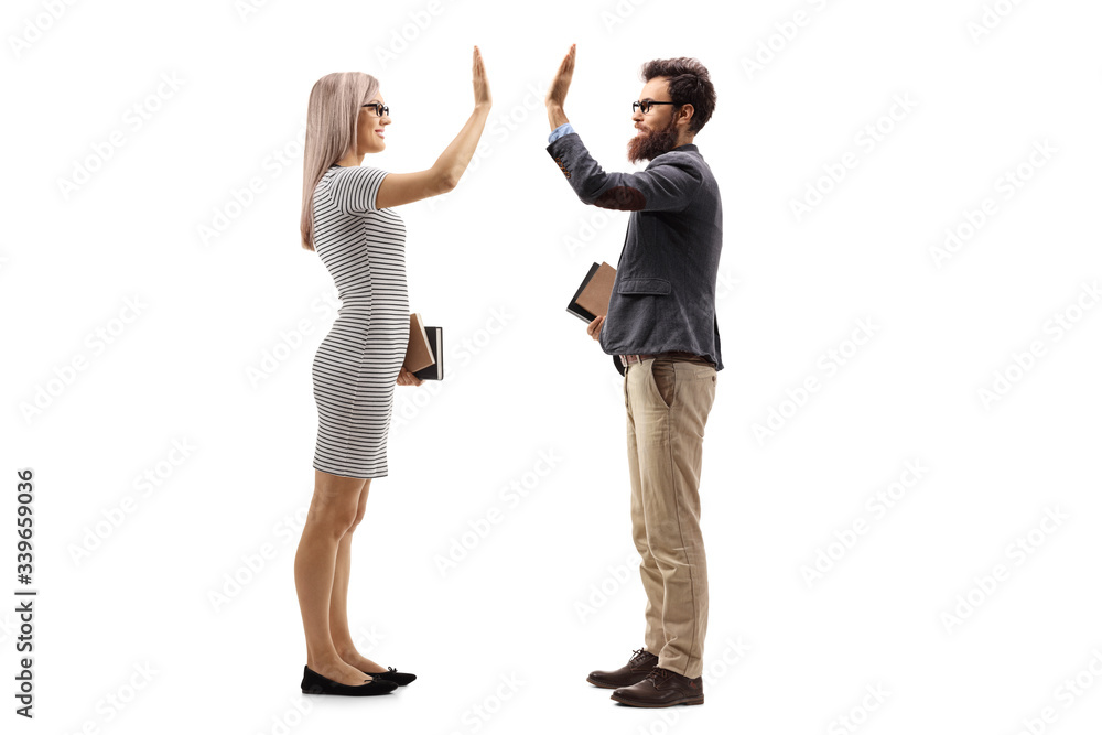 Blond young woman holding books and gesturing high-five with a bearded man Blond young woman holding books and gesturing high-five with a bearded man