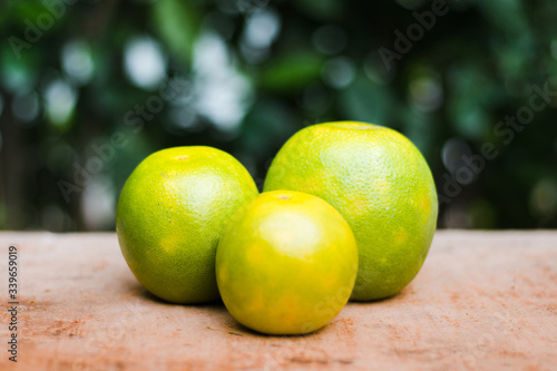 Three oranges of different sizes on a wooden table