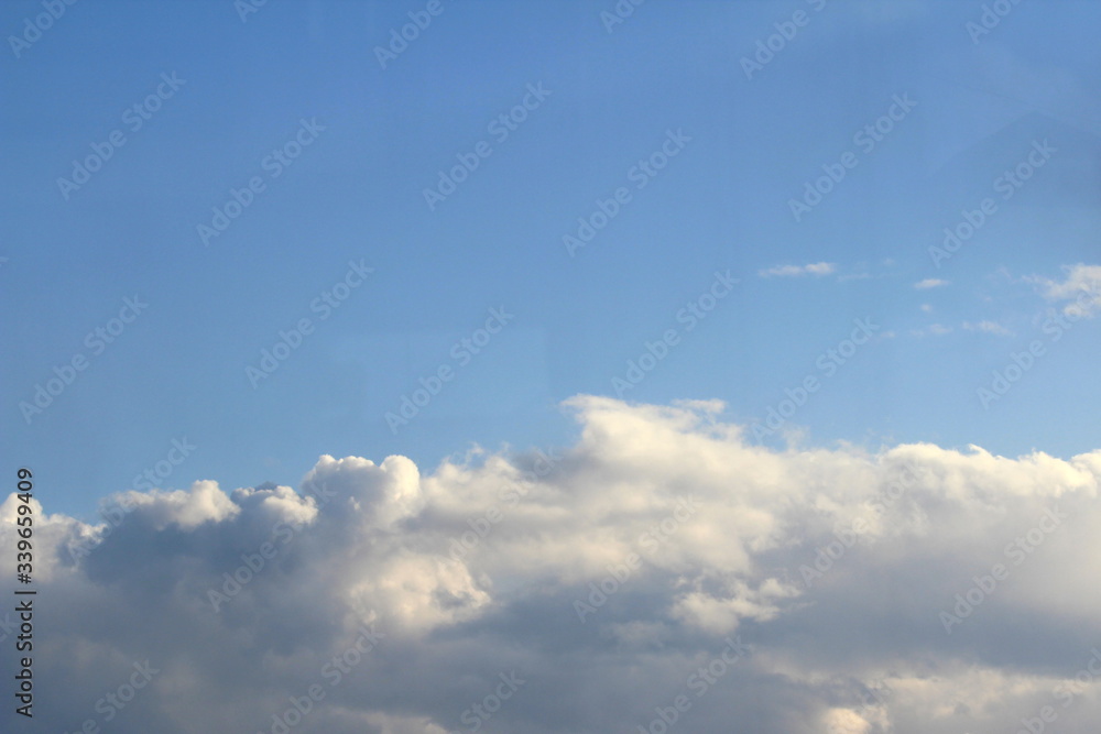 Clouds in the blue sky at sunset or dawn backlit by the sun. Place for text and design. Clouds in the blue sky at sunset or dawn backlit by the sun. Place for text and design.