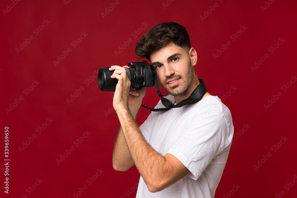 Young man over isolated background with a professional camera Young man over isolated background with a professional camera