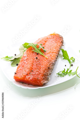 piece of salty red fish with different seasonings and herbs in a plate