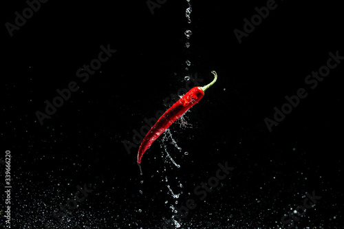 Red hot chili pepper flies in drops of water. Levitation