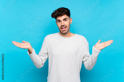 Young man over isolated blue background with shocked facial expression