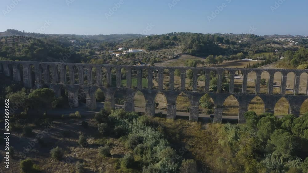 Flight over an ancient portuguese aqueduct of Pegoes. Europe Dolly shot. Sunset sun with lens flare. Old ruins surrounded by a green Park Flight over an ancient portuguese aqueduct of Pegoes. Europe Dolly shot. Sunset sun with lens flare. Old ruins surrounded by a green Park