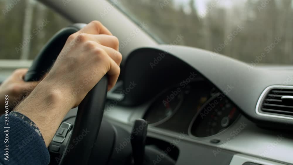 Close up man's hands on the steering wheel of moving car. Driver's point of view, POV. Dashboard Close up man's hands on the steering wheel of moving car. Driver's point of view, POV. Dashboard