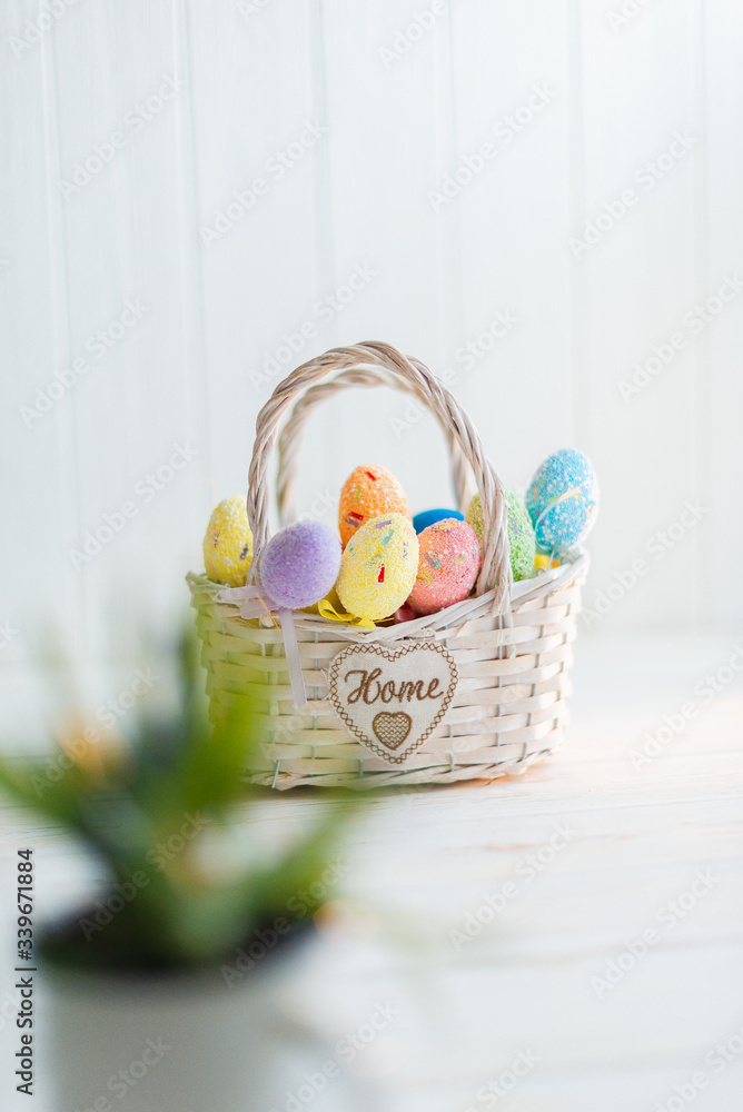 Multi-colored Easter eggs in a basket on a white wooden background Multi-colored Easter eggs in a basket on a white wooden background