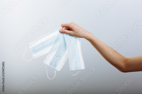 A women's hand holds a medical masks isolated in white background