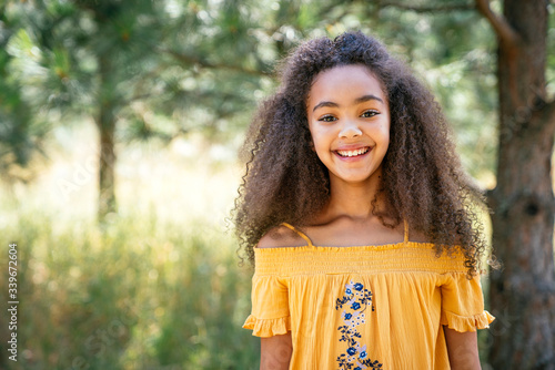 Portrait of smiling curly haired girl outside in nature