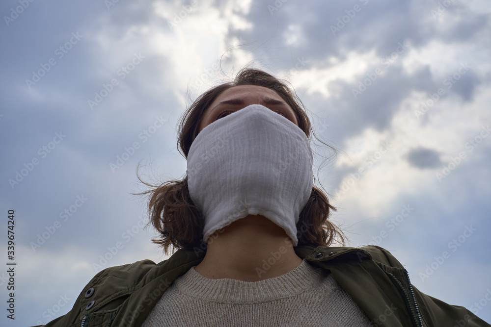 Girl in protective mask against the coronavirus on sky and nature background. World in post apocalypse after pandemic covid-19, quarantine and global catastrophe Girl in protective mask against the coronavirus on sky and nature background. World in post apocalypse after pandemic covid-19, quarantine and global catastrophe