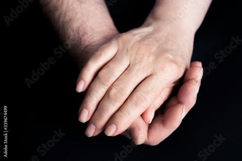 Hands of seniors men and women on a black paper background Hand of men touching senior women