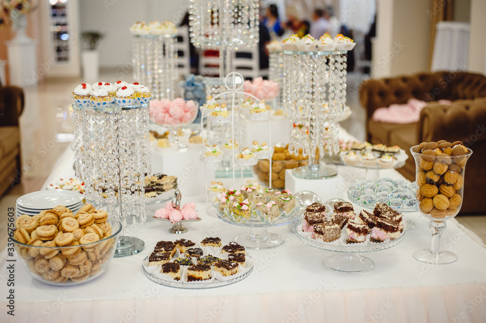 Beautifully decorated sweet buffet table on which cakes, muffins, marshmallows, pecans.  Dessert table for a party, goodies for the wedding. Close up. Candy bar. A buffet for a wedding