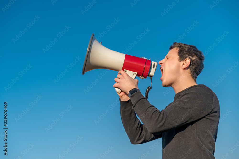 young man voices to megaphone warning of dangerous event. Copy space young man voices to megaphone warning of dangerous event. Copy space