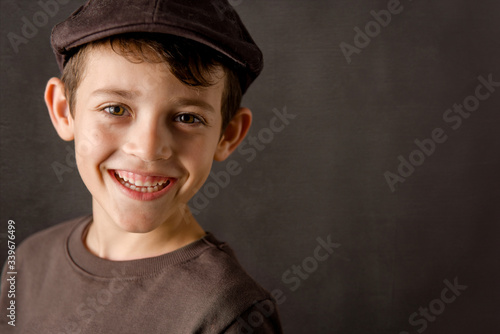 smiling kid looking at camera with a brown vintage cap