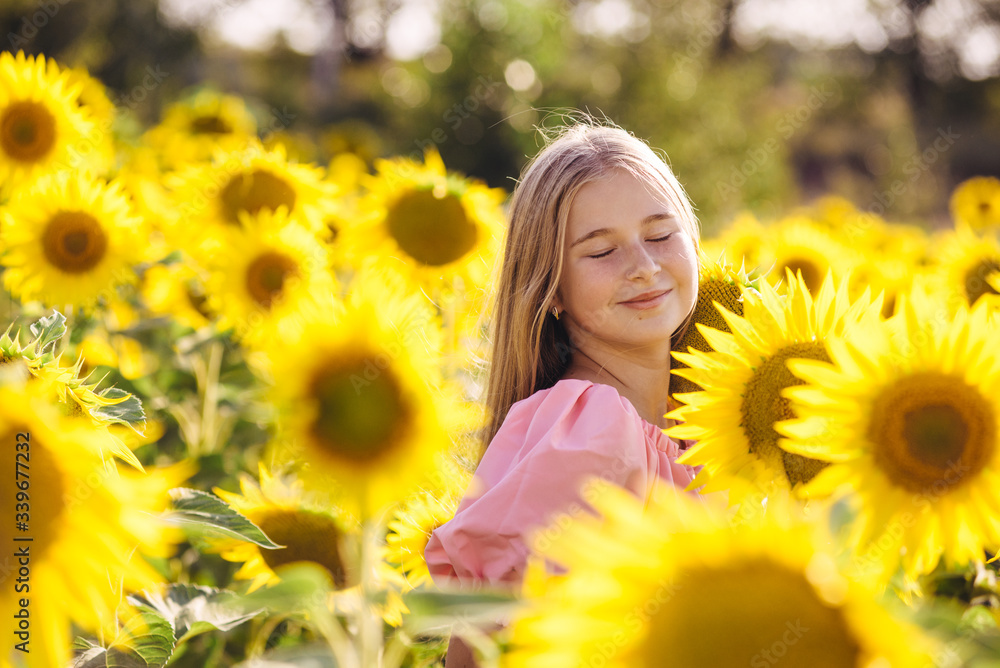 Cute girl in sunflower field posing for camera, harmony with nature, young model Cute girl in sunflower field posing for camera, harmony with nature, young model