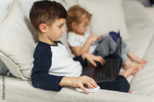 2 children, a boy and a girl sit at home and play games on the computer, quarantine classes at home