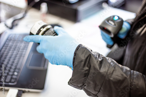 Obraz na plátně In a hardware store at the checkout, a store employee in blue medical gloves is working during quarantine