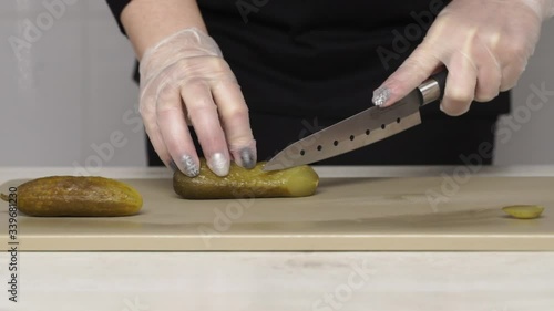 Chef cuts satled cucumbers or pickled cucumber on plastic board photo