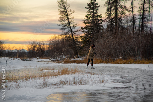 Woman skating on frozen lake in wild & isolated Yukon Territory, northern Canada. Active, activity, outside in Canada. 