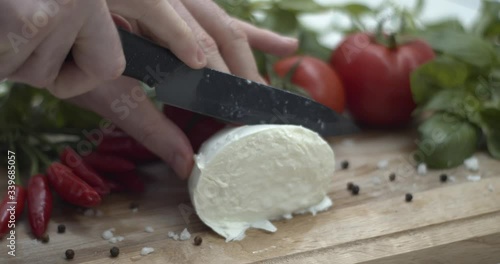 Tagliare mozzarella di bufala su un tagliere per preparare una caprese, ricetta italiana