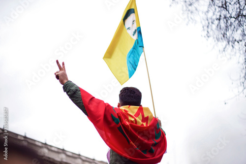 kurdish activist waves flags and makes victory gesture