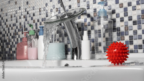 Canvas Print The red covid-19 coronavirus molecule is on the white washstand in the bathroom