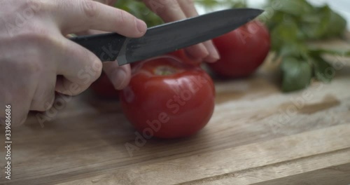 Tagliare un pomodoro su un tagliere per preparare una buona caprese con mozzarella di bufala