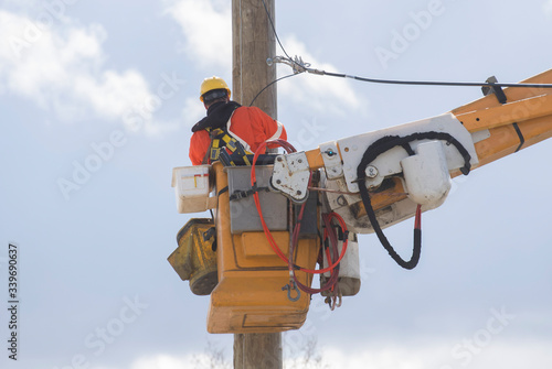 A lineworker is shown working on a utility pole