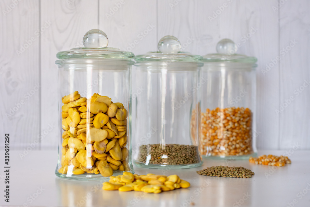 Dried Beans, lentils and nuts in jars on a table in front of a wooden wall Dried Beans, lentils and nuts in jars on a table in front of a wooden wall