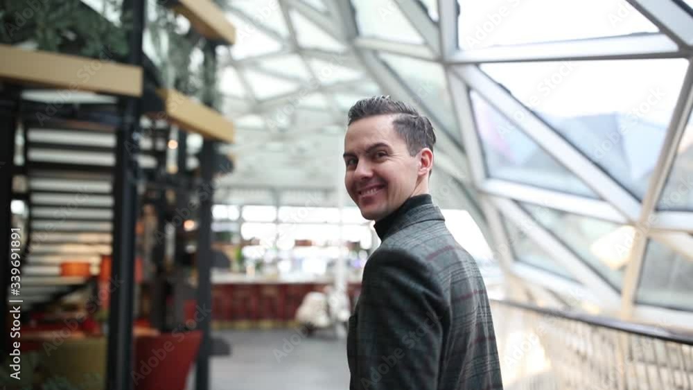 The guy walks under the glass dome of the mall and smiles at the camera The guy walks under the glass dome of the mall and smiles at the camera