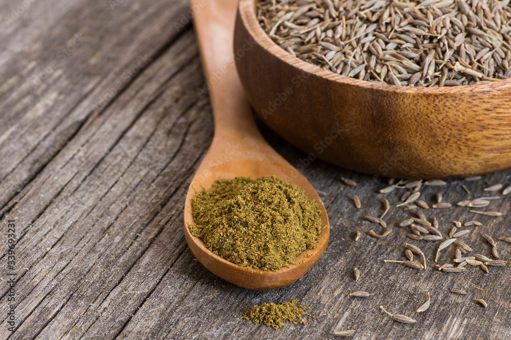 Pile of dry caraway spice with ground caraway powder in wooden spoon. Healthy food cumin spice concept ( Cuminum cyminum ) Pile of dry caraway spice with ground caraway powder in wooden spoon. Healthy food cumin spice concept ( Cuminum cyminum )