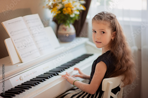 Home lesson on music for the girl on the piano. The idea of activities for the child at home during quarantine. Music concept