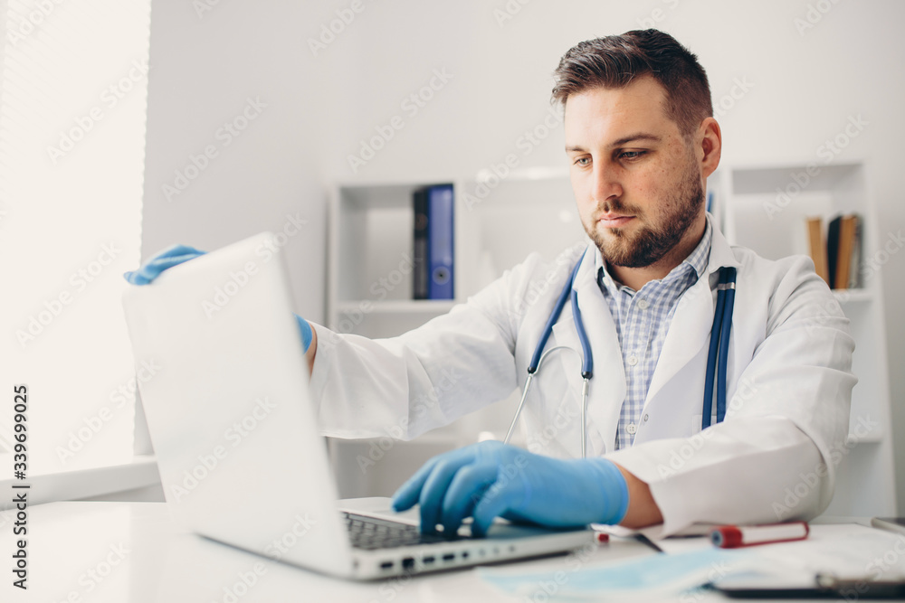Young handsome doctor in gloves with patient online consultate