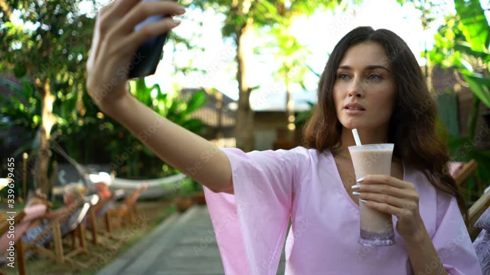 Young woman with drink taking selfie photo with cellphone in park cafe Young woman with drink taking selfie photo with cellphone in park cafe