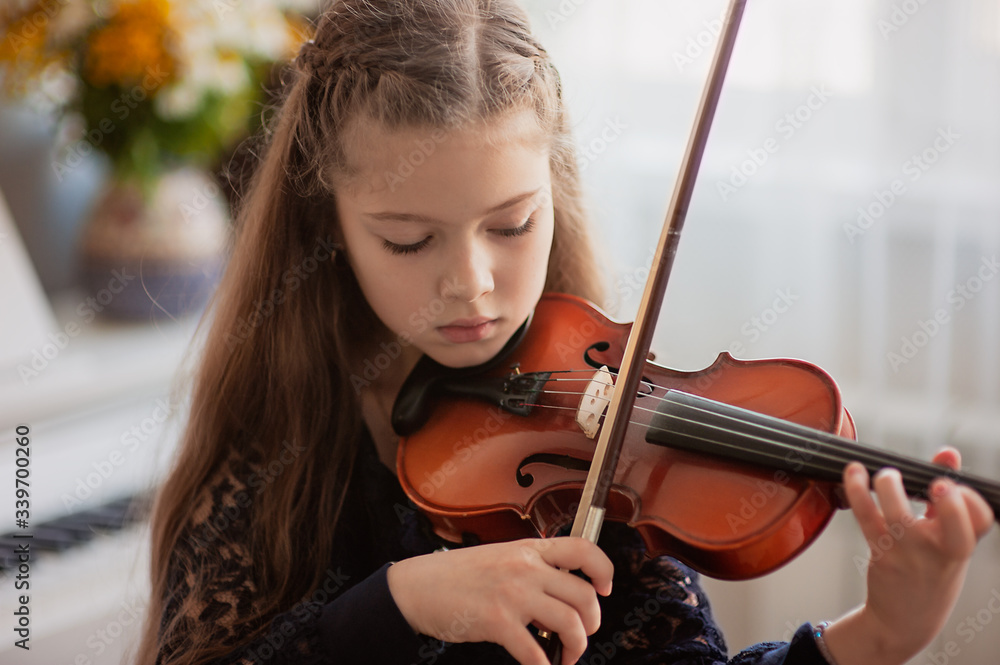 Home lesson for a girl playing the violin. The idea of activities for children during quarantine. Music concept Home lesson for a girl playing the violin. The idea of activities for children during quarantine. Music concept