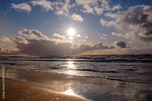 The Baltic Sea coast in winter  the sun shines brightly and there are clouds in the sky  but there are waves in the sea