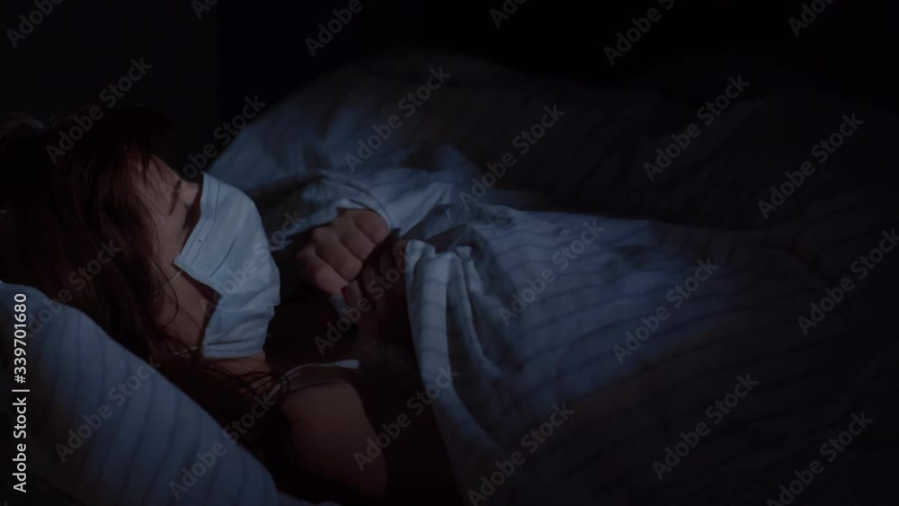 woman in medical mask lies on the bed and coughs woman in medical mask lies on the bed and coughs