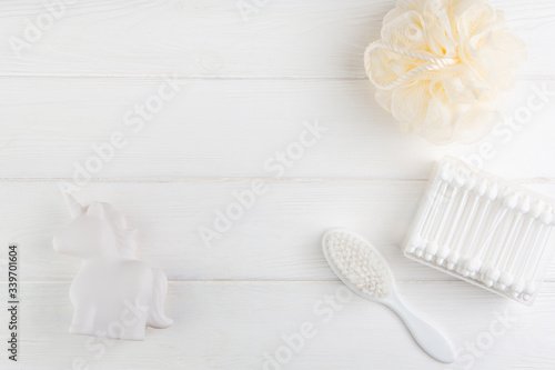 Spa and bath concept. Baby bath set. Washcloth, hair brush, ear sticks and rubber unicorn on a white background.