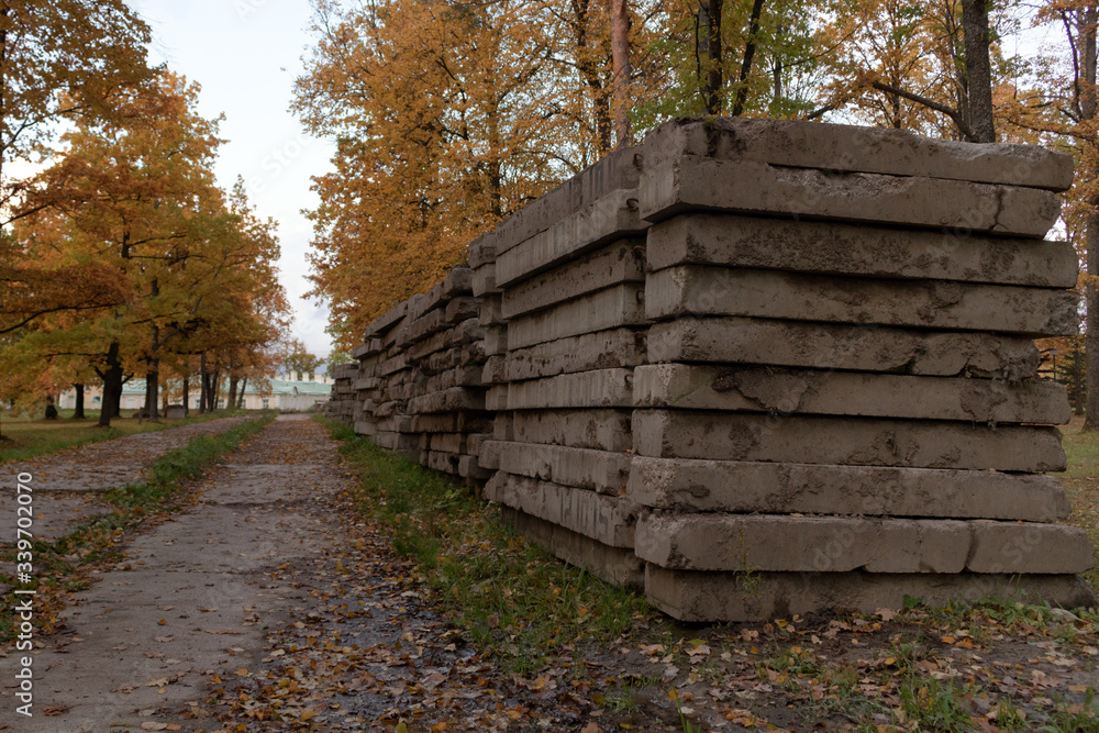 Old concrete slabs piled on the edge of a dirt track in autumn