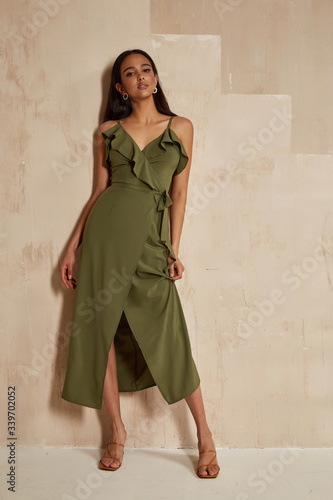 Billede på lærred Fashion model brunette hair wear green silk dress sandals high heels accessory bag clothes for date party walk interior  Sahara journey summer collection wall stairs beautiful woman sexy jewelry
