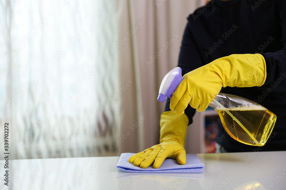 cleaner's hands in rubber yellow gloves doing disinfection cleaning with detergent spray and rag. preventive measures against coronavirus infection