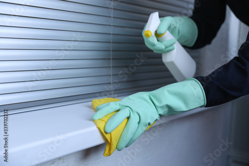 cleaner's hands in rubber mint gloves doing disinfection cleaning with detergent spray and rag. preventive measures against covid-19