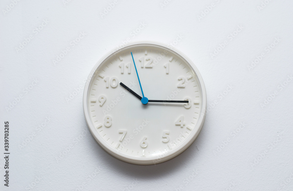 White wall clock hanging on a white wall White wall clock hanging on a white wall