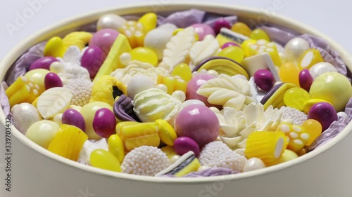 Round box filled with colorful handmade chocolates, side view, circular rotation