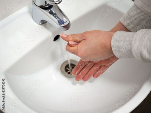 Proper hand washing with liqud soap under the faucet with water to completely disinfect and prevent the coronavirus germs spreading pandemic. Hygiene and health- cleanliness concept.