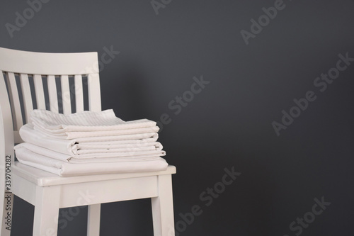 Photography Ironed and folded white striped bed clothes on a white table on dark grey wall b