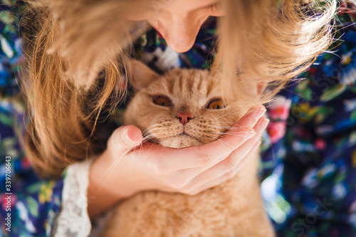 Fotografie Woman is hugging orange tabby feline