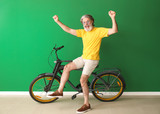 Happy elderly man with bicycle near color wall